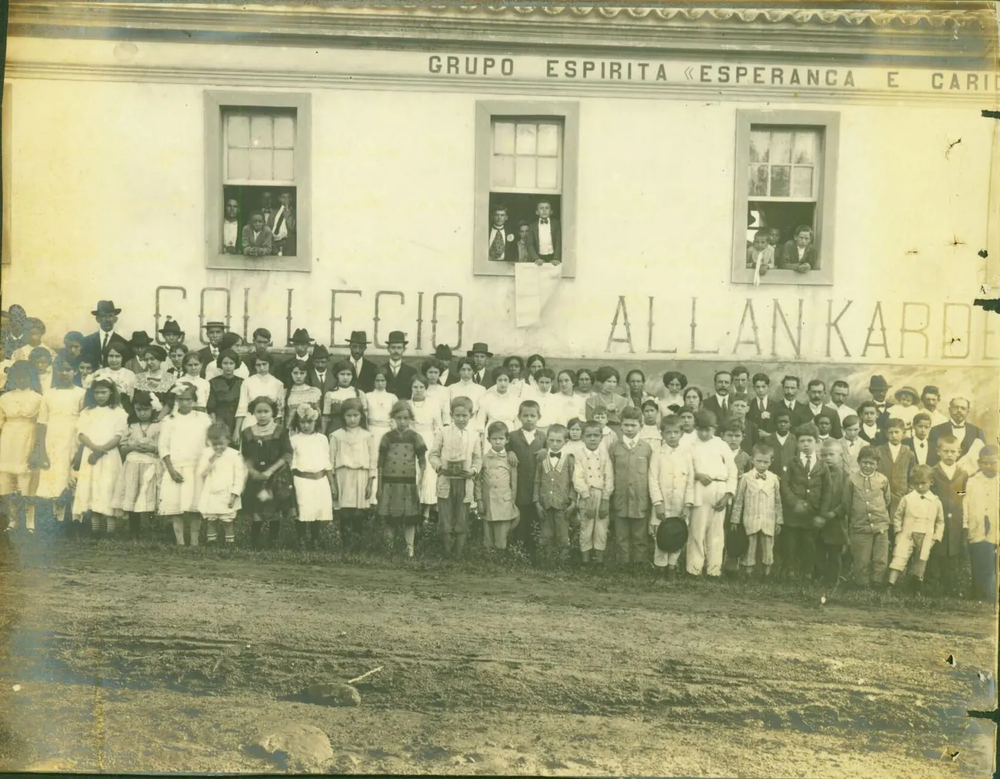 Fotografia antiga de alunos e professores diante do prédio com a inscrição Collegio Allan Kardec