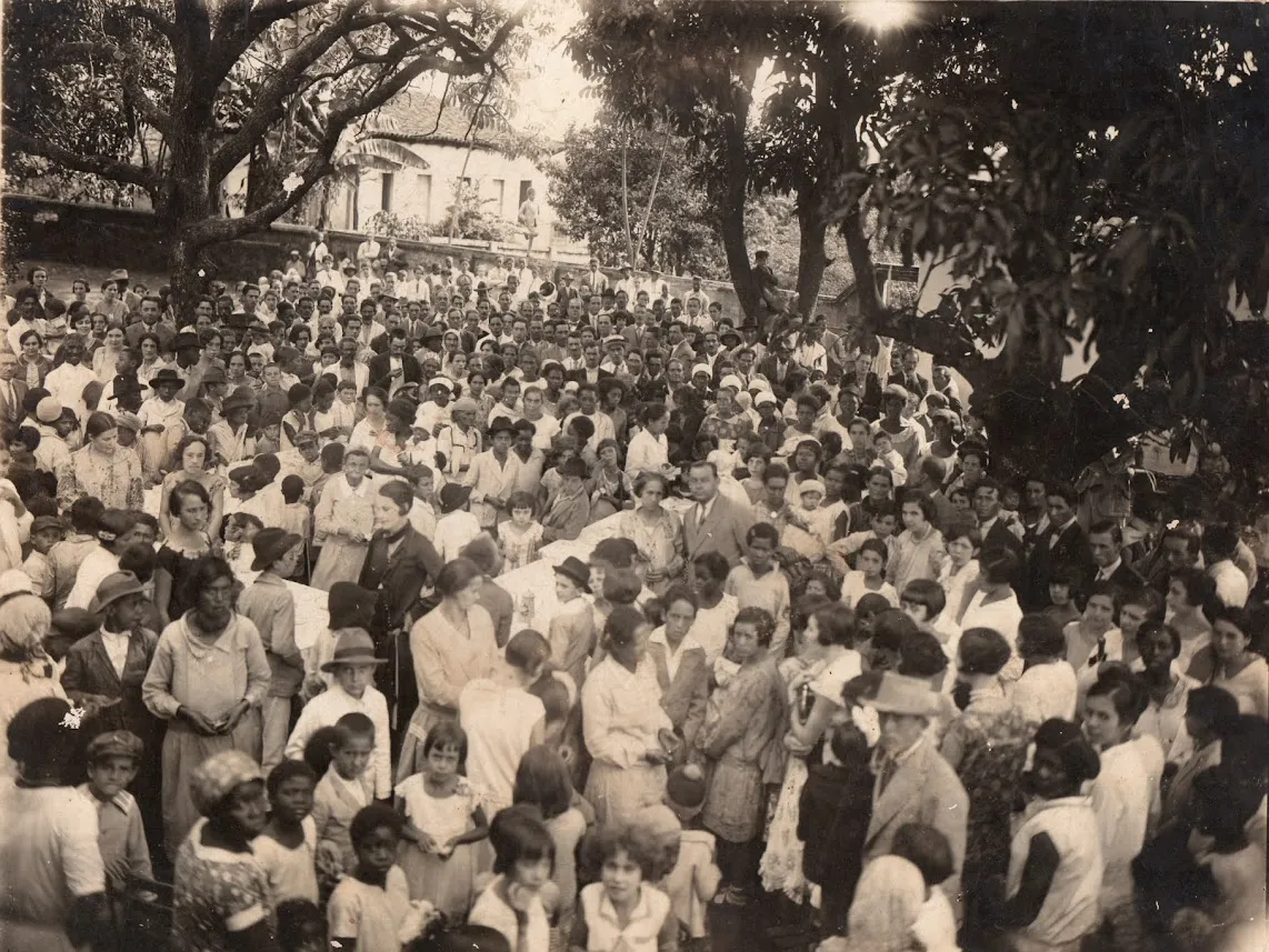 Multidão sob árvores, em fotografia antiga