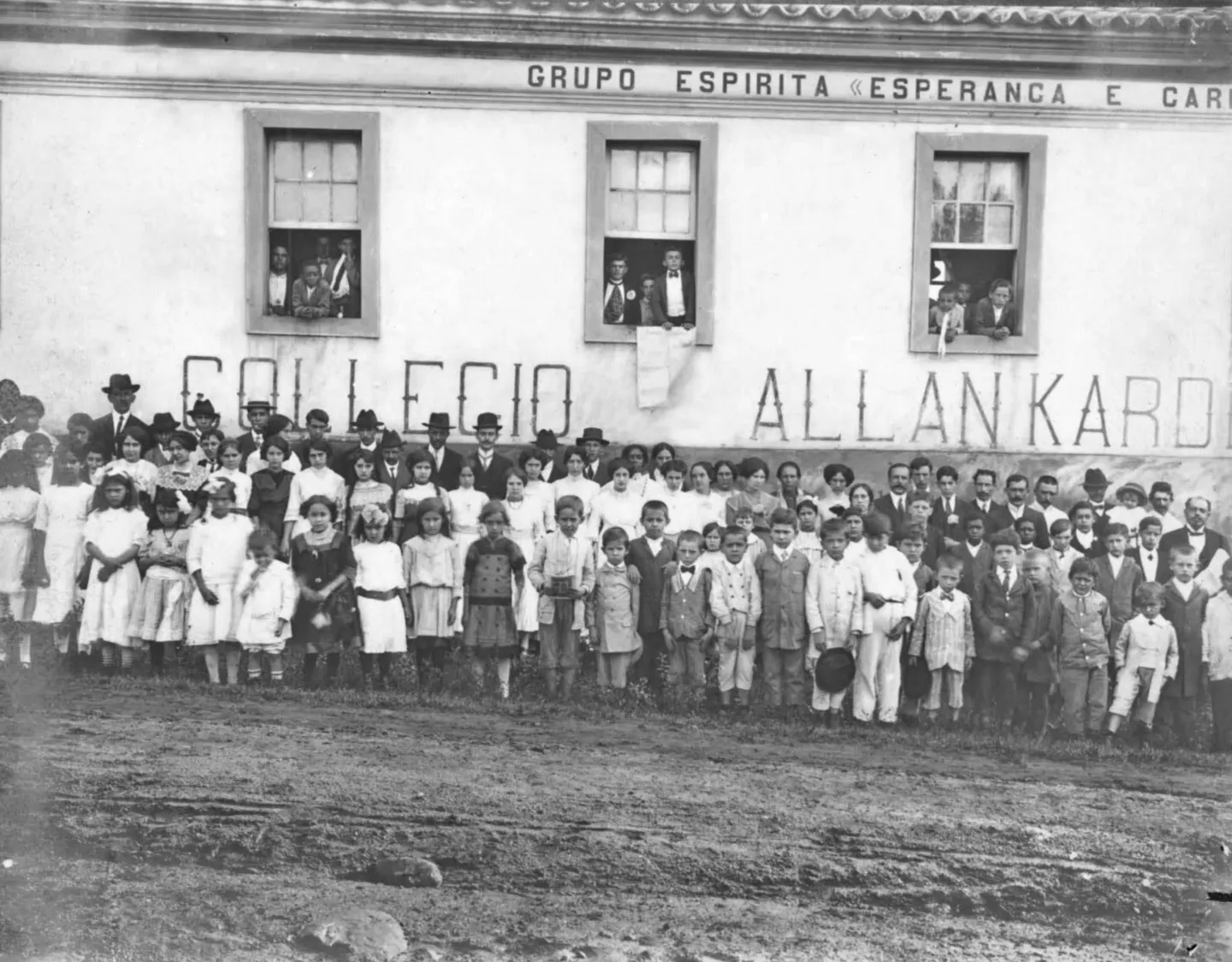 Fotografia antiga de alunos e professores diante do prédio com a inscrição Collegio Allan Kardec